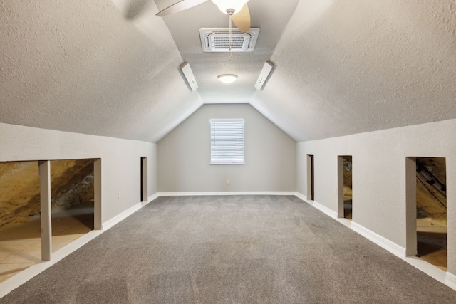 bonus room with carpet, visible vents, vaulted ceiling, a textured ceiling, and baseboards