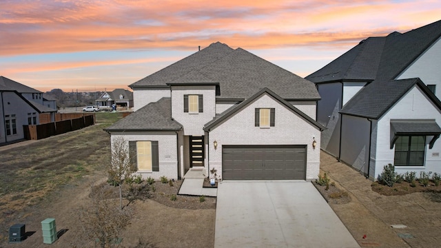 view of front of property featuring an attached garage, concrete driveway, brick siding, and a shingled roof