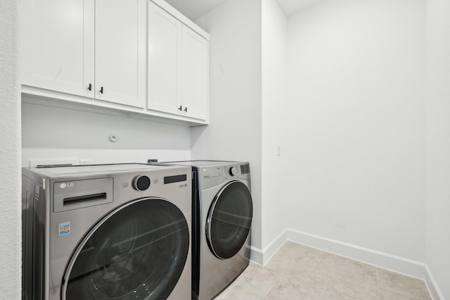 washroom with cabinet space, baseboards, washer and clothes dryer, and light tile patterned flooring