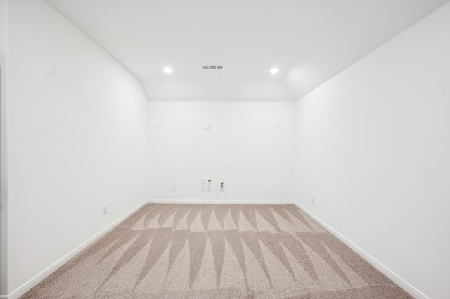 spare room with baseboards, visible vents, vaulted ceiling, and light colored carpet