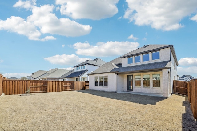 back of house with a patio, a fenced backyard, brick siding, roof with shingles, and a residential view