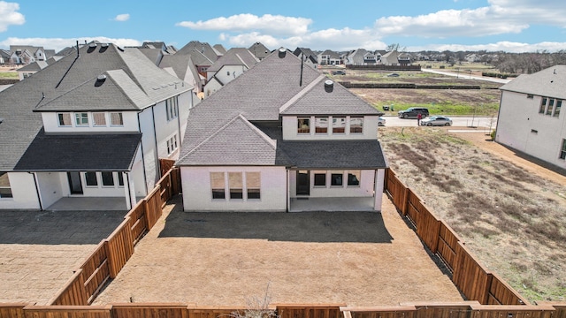 view of front of property featuring a fenced backyard, a residential view, a shingled roof, and a patio