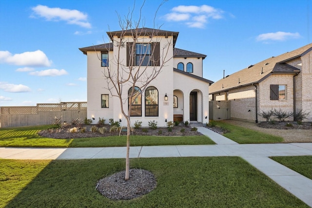 mediterranean / spanish-style home featuring a front lawn and fence