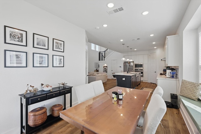 dining area featuring visible vents, wood finished floors, recessed lighting, and stairs