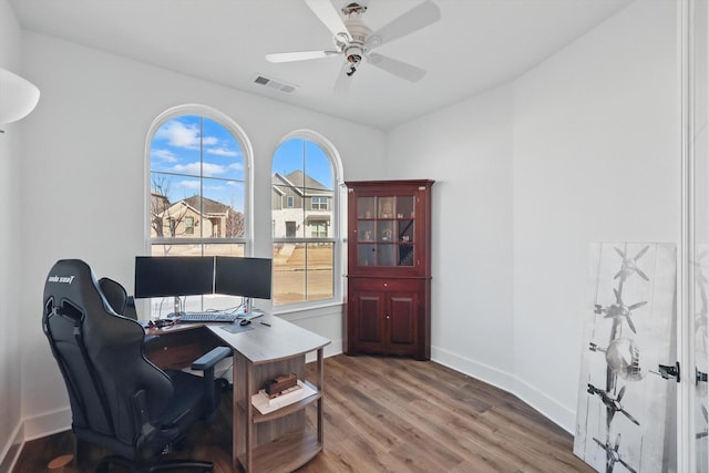 office area with baseboards, a ceiling fan, wood finished floors, and visible vents