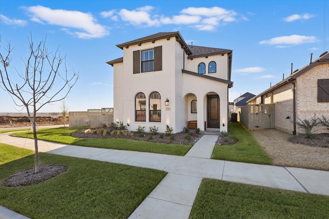 mediterranean / spanish-style home with a front lawn, fence, and a gate