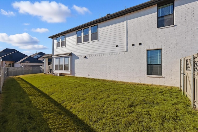 rear view of house with brick siding, a lawn, and a fenced backyard