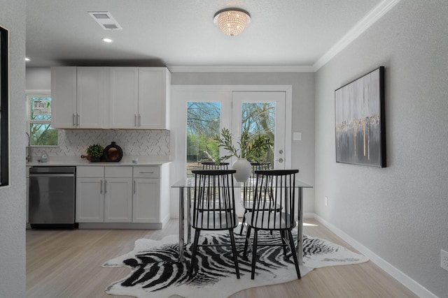 dining area with a wealth of natural light, visible vents, light wood-style flooring, and baseboards