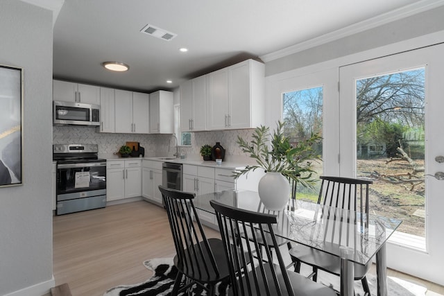 kitchen with stainless steel appliances, light countertops, white cabinets, and visible vents