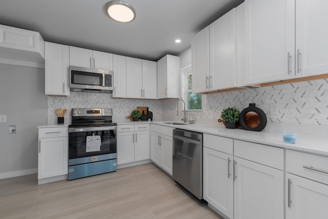 kitchen with white cabinetry, appliances with stainless steel finishes, light countertops, and a sink