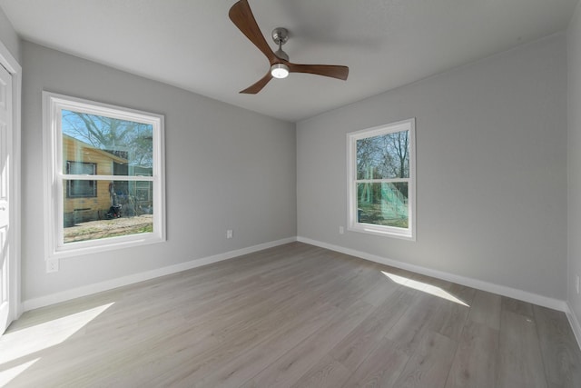 spare room featuring light wood finished floors, ceiling fan, and baseboards