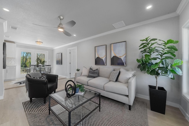 living room with light wood-type flooring, visible vents, and crown molding