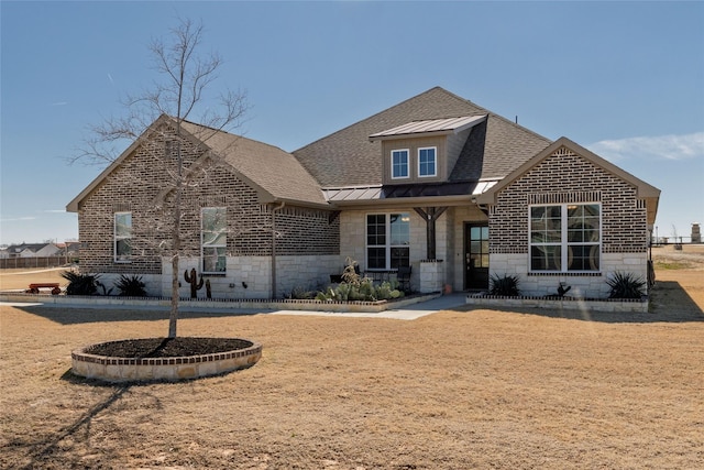 view of front facade with stone siding, metal roof, roof with shingles, a standing seam roof, and brick siding