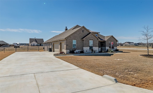 french country home with driveway, stone siding, an attached garage, and fence