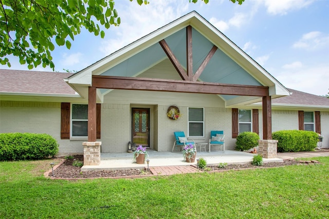 view of front of home with roof with shingles, a front lawn, and brick siding