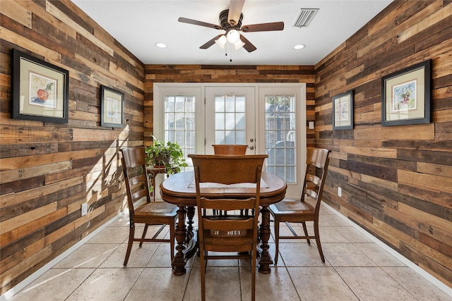 dining area featuring ceiling fan, wood walls, and visible vents