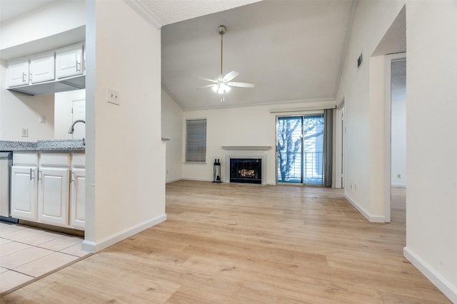 unfurnished living room with light wood-type flooring, a fireplace, lofted ceiling, and ceiling fan