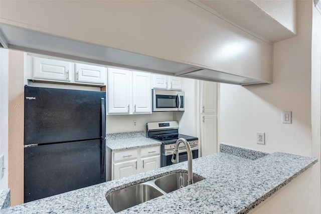 kitchen featuring stainless steel appliances, white cabinetry, a sink, and light stone counters