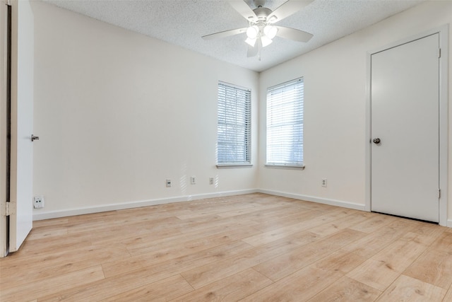 empty room with a textured ceiling, ceiling fan, baseboards, and light wood-style floors