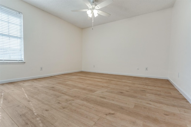 empty room with ceiling fan, a textured ceiling, light wood-style flooring, and baseboards