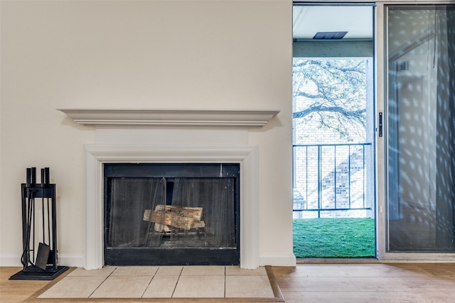 room details featuring wood finished floors, a fireplace with flush hearth, and baseboards