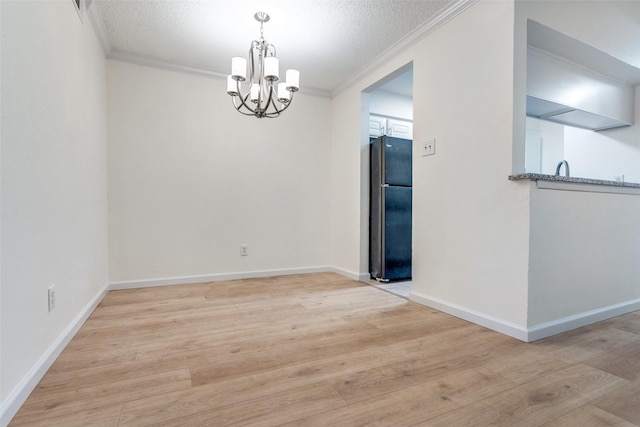 unfurnished dining area with light wood-type flooring, ornamental molding, and a textured ceiling