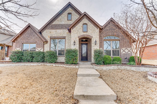 french country style house with stone siding and brick siding