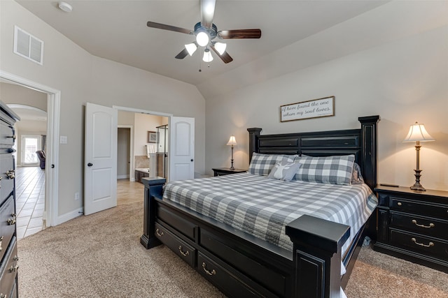 bedroom with arched walkways, lofted ceiling, connected bathroom, light colored carpet, and visible vents