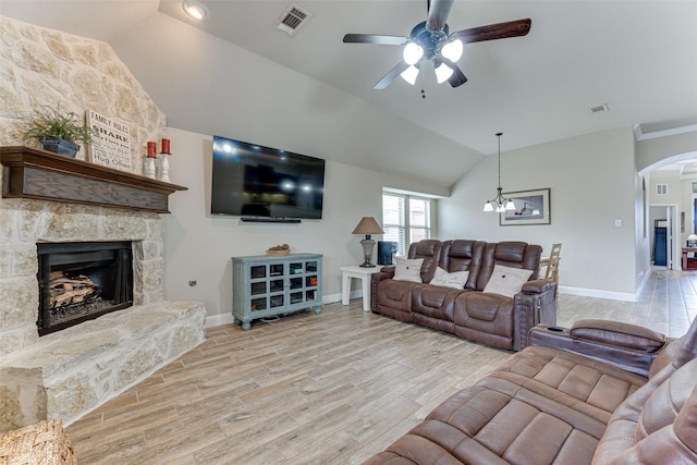 living room featuring light wood-style floors, visible vents, arched walkways, and vaulted ceiling