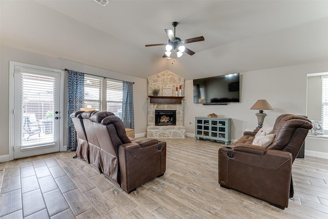 living area with lofted ceiling, a stone fireplace, a ceiling fan, baseboards, and light wood finished floors