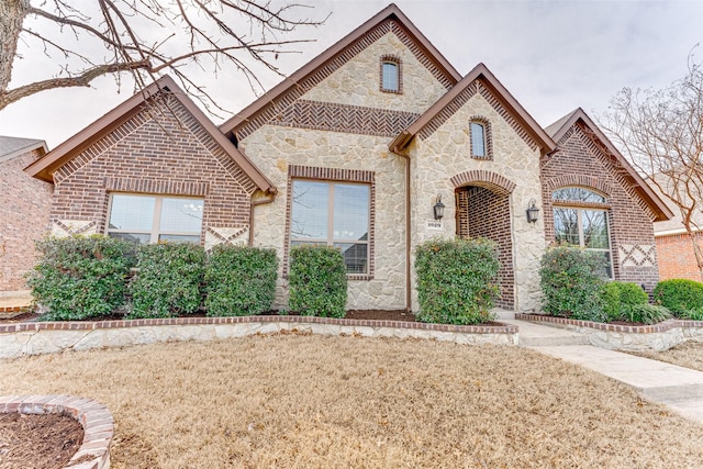 french country inspired facade with stone siding and brick siding