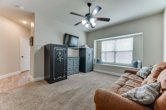 living area with light carpet, ceiling fan, and baseboards