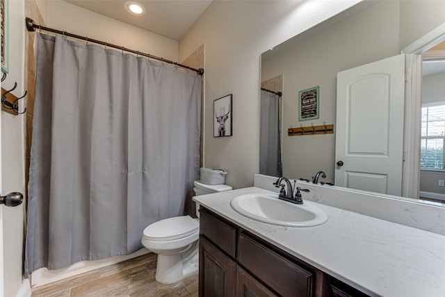 bathroom featuring toilet, curtained shower, wood finished floors, and vanity