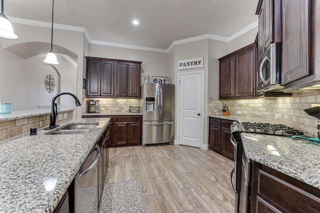 kitchen featuring appliances with stainless steel finishes, a sink, dark brown cabinetry, and light stone countertops