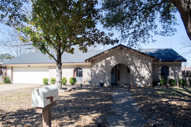 view of front of property featuring a garage, concrete driveway, brick siding, and roof with shingles