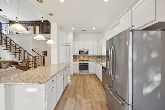 kitchen featuring stainless steel appliances, hanging light fixtures, backsplash, white cabinetry, and light stone countertops