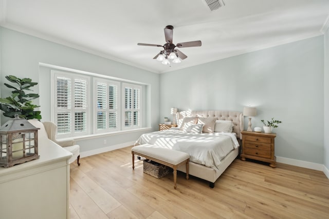 bedroom featuring ornamental molding, light wood-type flooring, visible vents, and baseboards