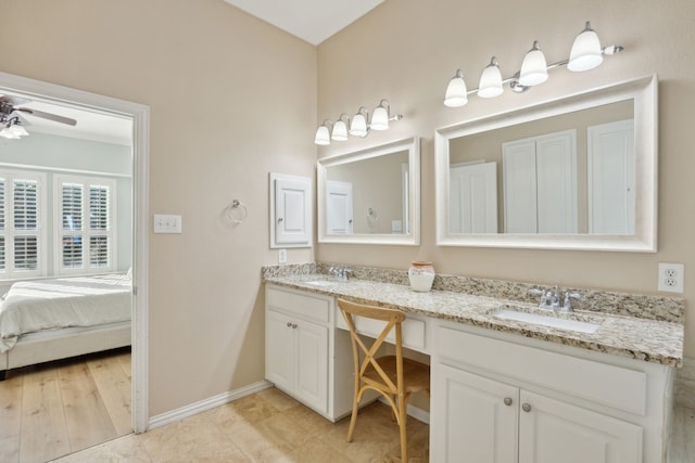 full bath with double vanity, a sink, a ceiling fan, and baseboards