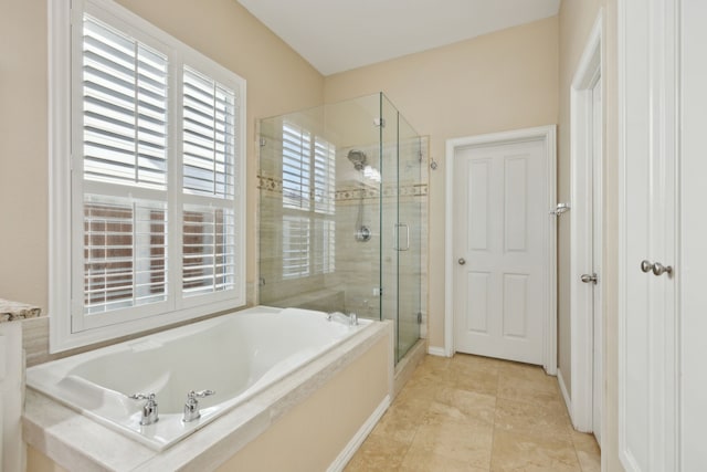 bathroom with a garden tub, a shower stall, baseboards, and tile patterned flooring