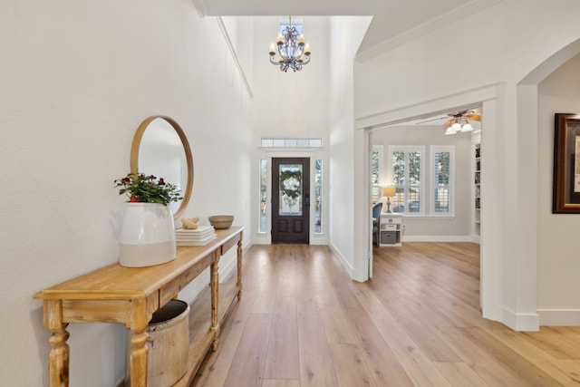 entrance foyer with ceiling fan with notable chandelier, baseboards, wood finished floors, and ornamental molding