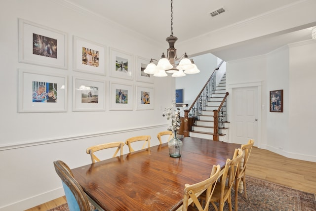 dining space featuring stairs, visible vents, crown molding, and wood finished floors