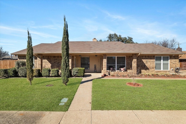 ranch-style home with brick siding, a chimney, fence, and a front yard