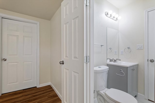 bathroom with toilet, baseboards, wood finished floors, and vanity