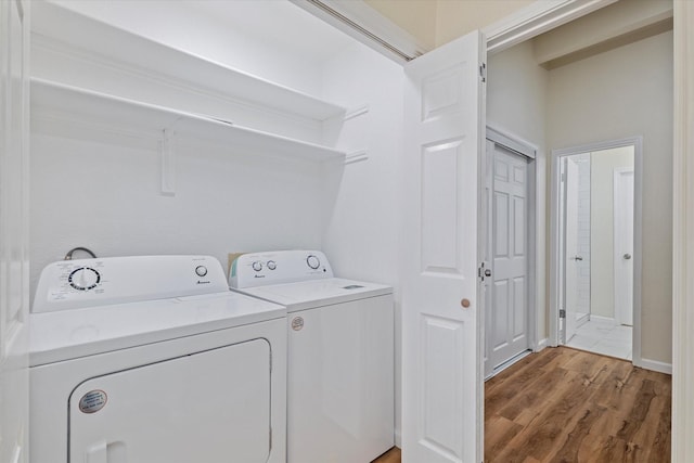 washroom featuring wood finished floors, laundry area, and separate washer and dryer