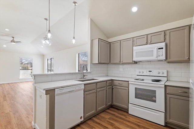 kitchen featuring pendant lighting, open floor plan, a sink, white appliances, and a peninsula