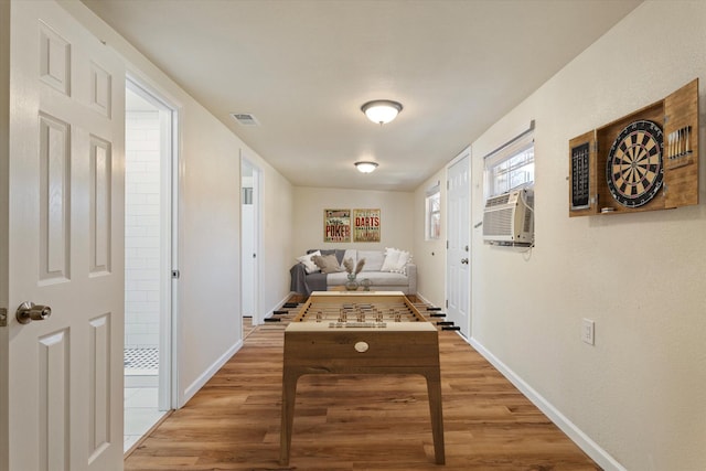 game room featuring a wall unit AC, wood finished floors, visible vents, and baseboards