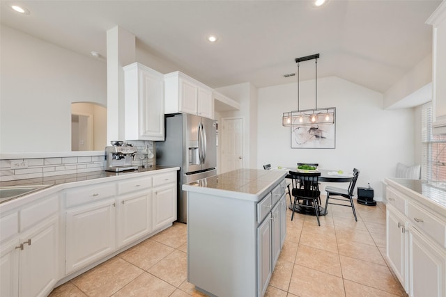 kitchen featuring tile countertops, white cabinets, vaulted ceiling, a center island, and pendant lighting