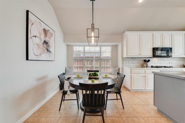 dining space with vaulted ceiling, baseboards, and light tile patterned floors