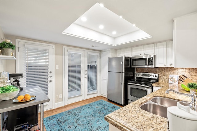 10211 Regal Oaks Dr Unit 121, Dallas, TX 75230 - kitchen with stainless steel appliances, a sink, light wood-style floors, light stone counters, and white cabinets