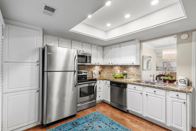 10211 Regal Oaks Dr Unit 121, Dallas, TX 75230 - kitchen featuring stainless steel appliances, a sink, white cabinets, light wood finished floors, and recessed lighting